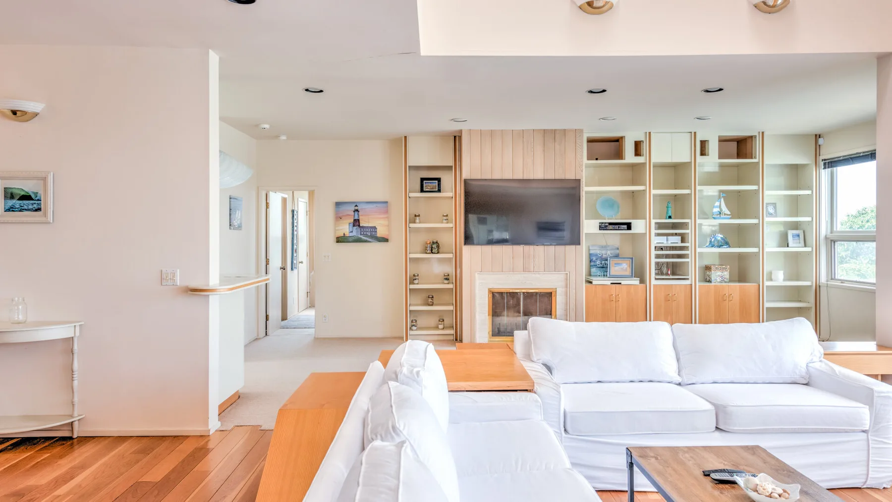 Una sala luminosa con asientos blancos, chimenea y estanterías empotradas.