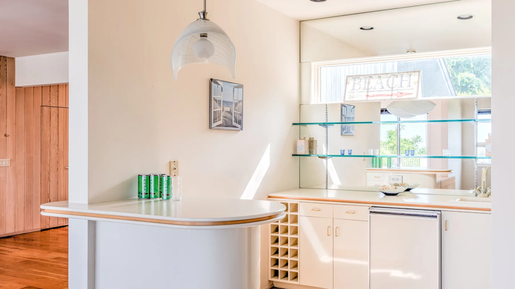 Una cocina luminosa con una barra curva, gabinetes y ventanas grandes.