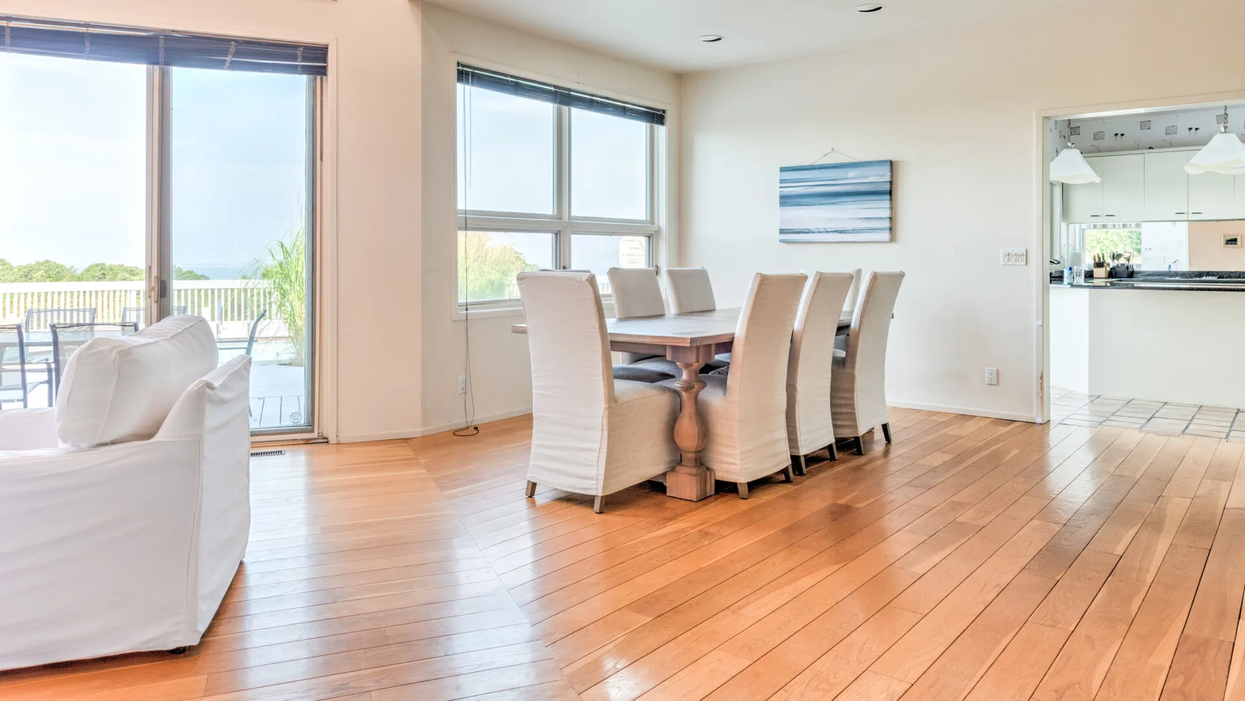 Un comedor luminoso con una mesa y asientos junto a grandes ventanas.