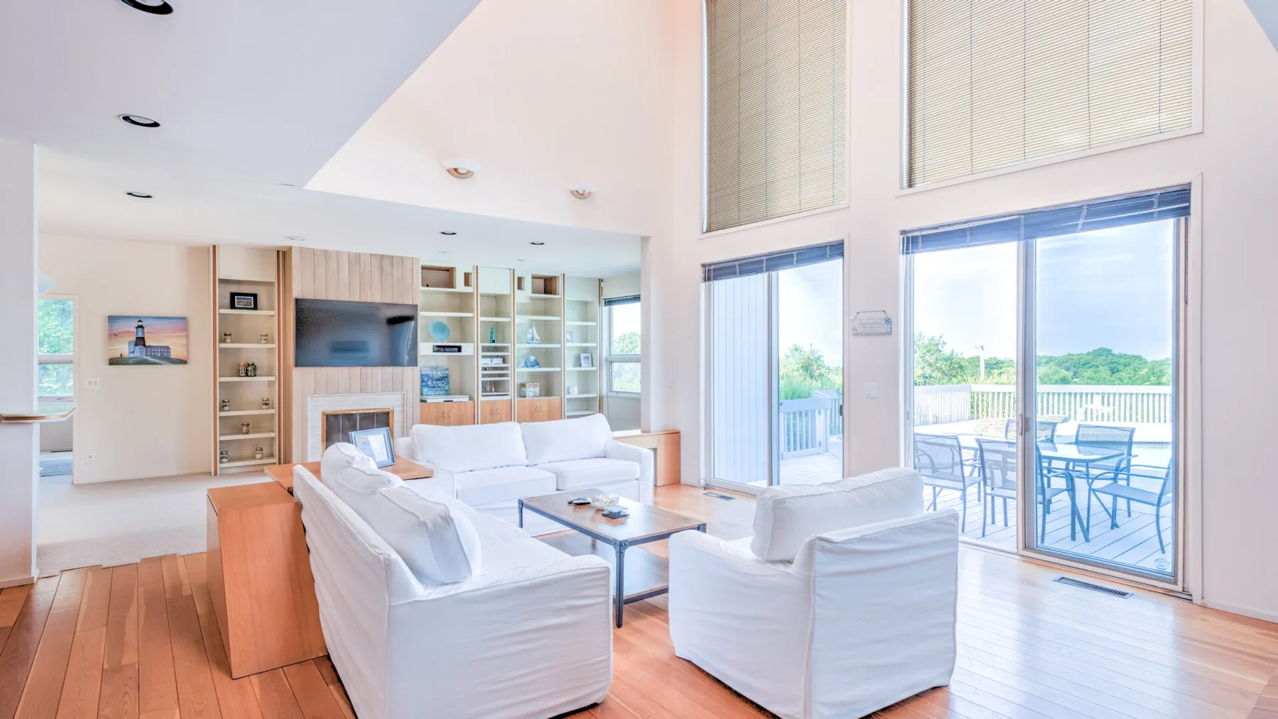 Una sala luminosa con asientos, una mesa de centro y grandes ventanas que dan a un patio.