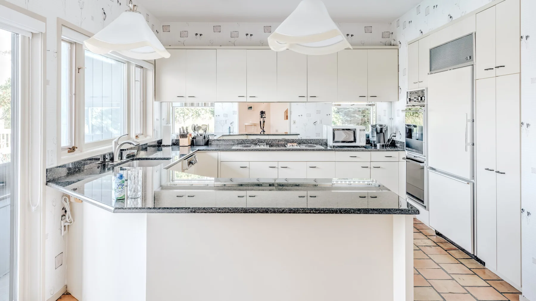 Una cocina luminosa con gabinetes blancos y una gran isla central.