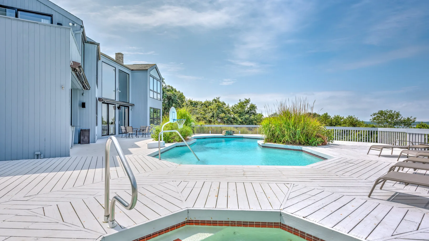 Una zona de piscina al aire libre con un spa elevado y asientos de descanso.