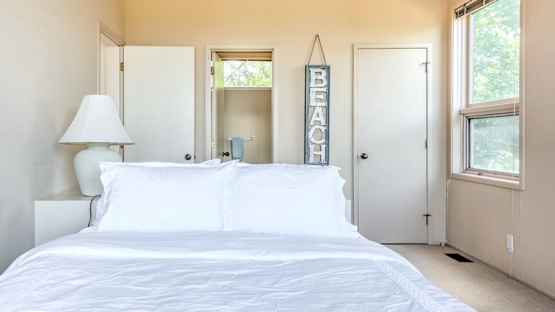 Un dormitorio luminoso con una cama tendida y ventanas en la pared.
