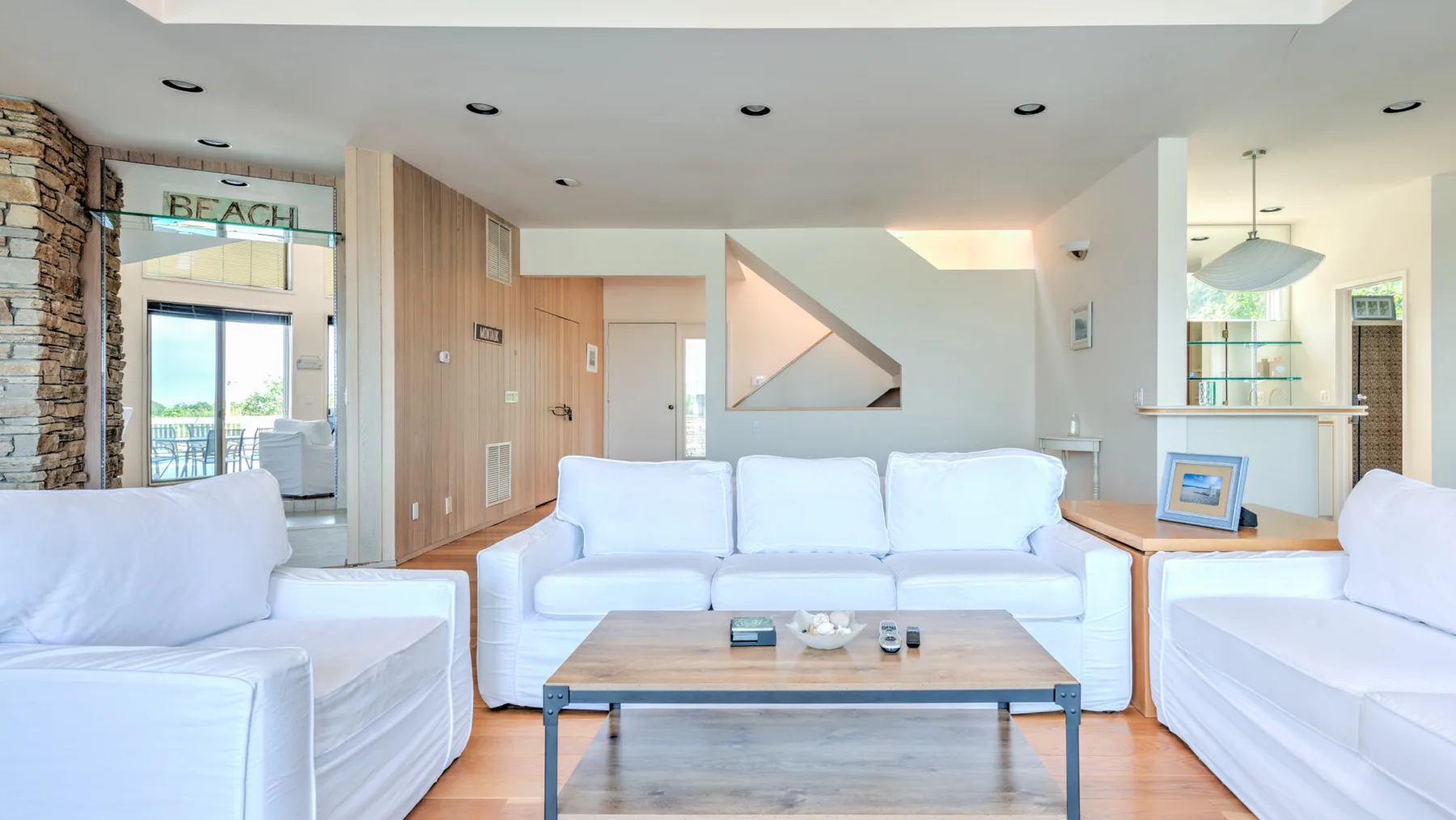 Una sala luminosa con asientos blancos y una mesa de centro de madera.