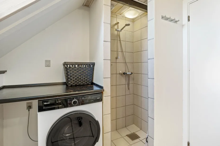 A compact bathroom with a washing machine beside a tiled shower.