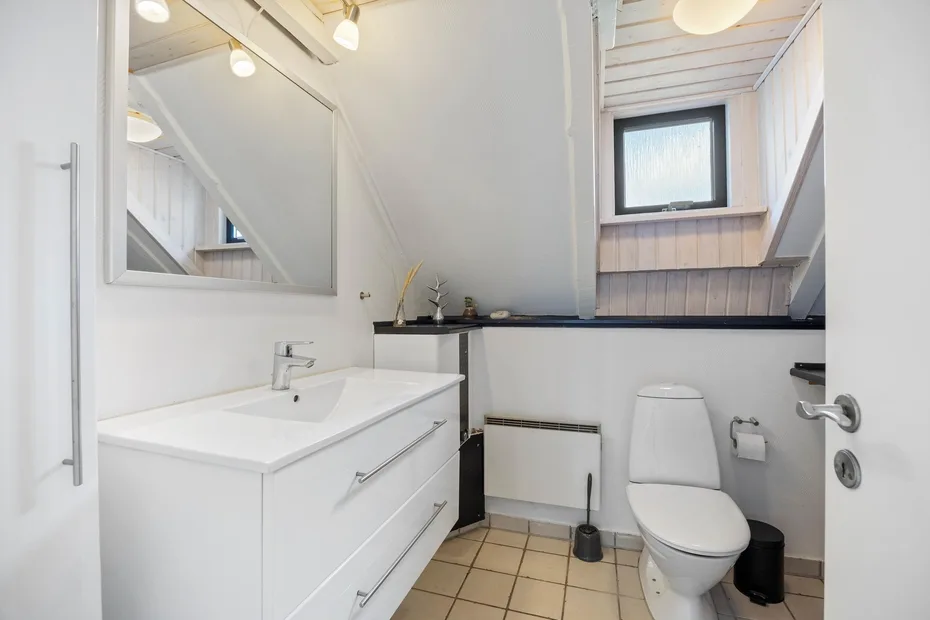 A bright bathroom with a sink, mirror, and toilet.