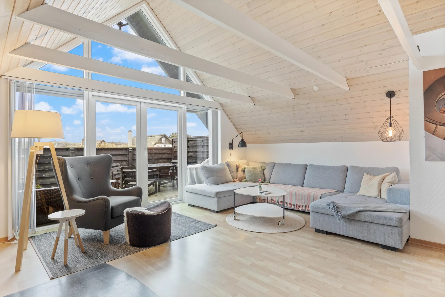 A bright living room with seating beneath a high, sloped ceiling.