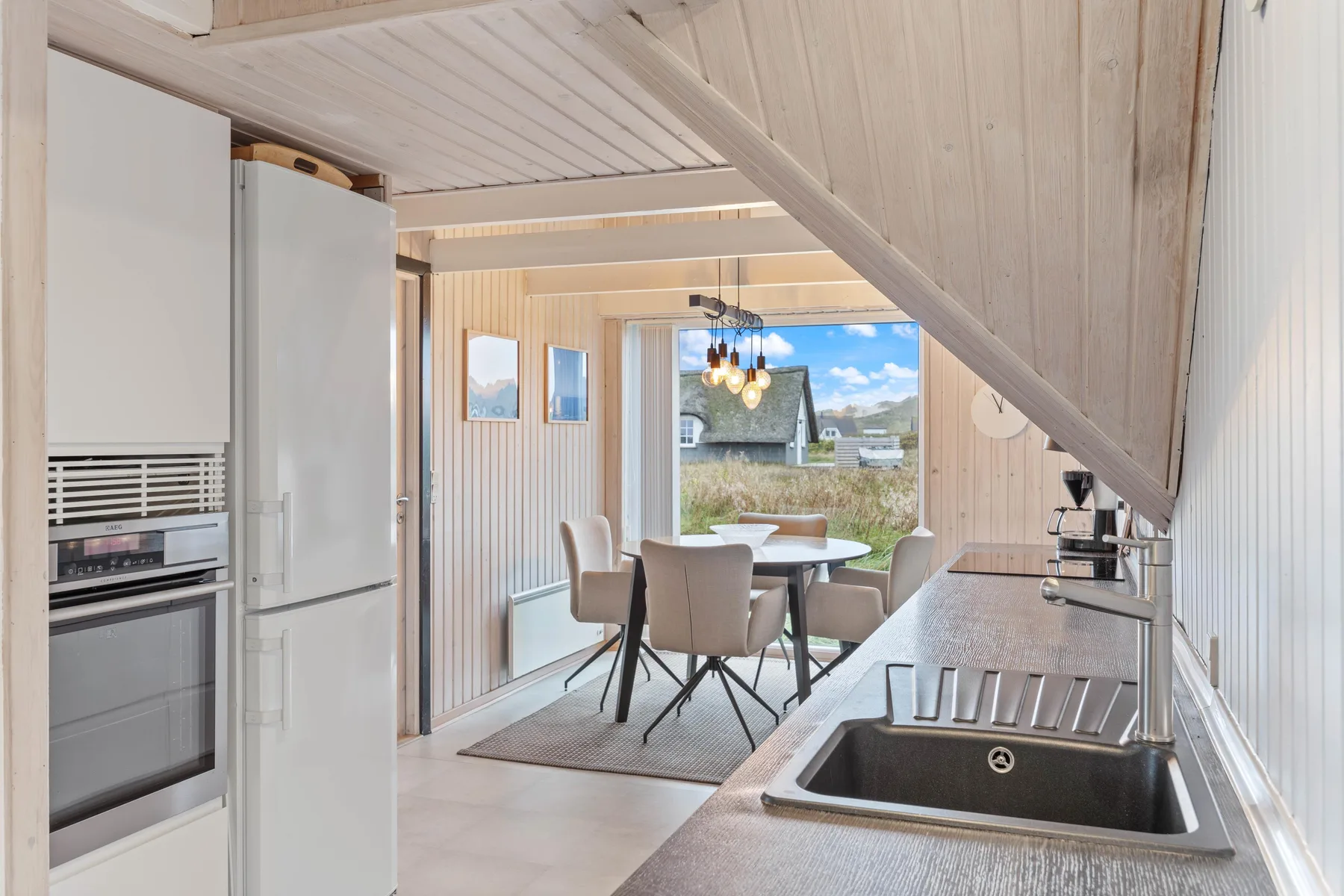 A bright kitchen and dining area with a table, seating, and a sink.