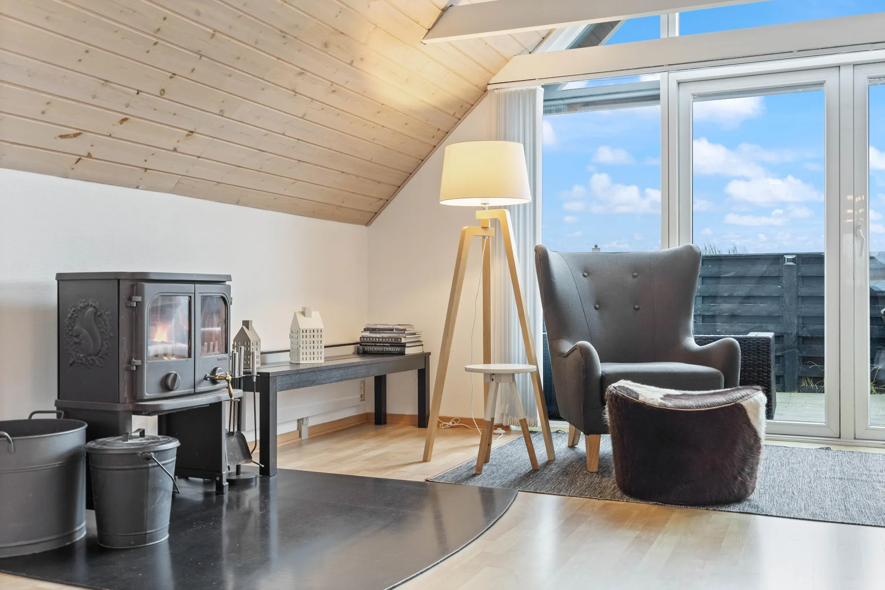 A bright attic sitting area with a tall floor lamp beside a large window.