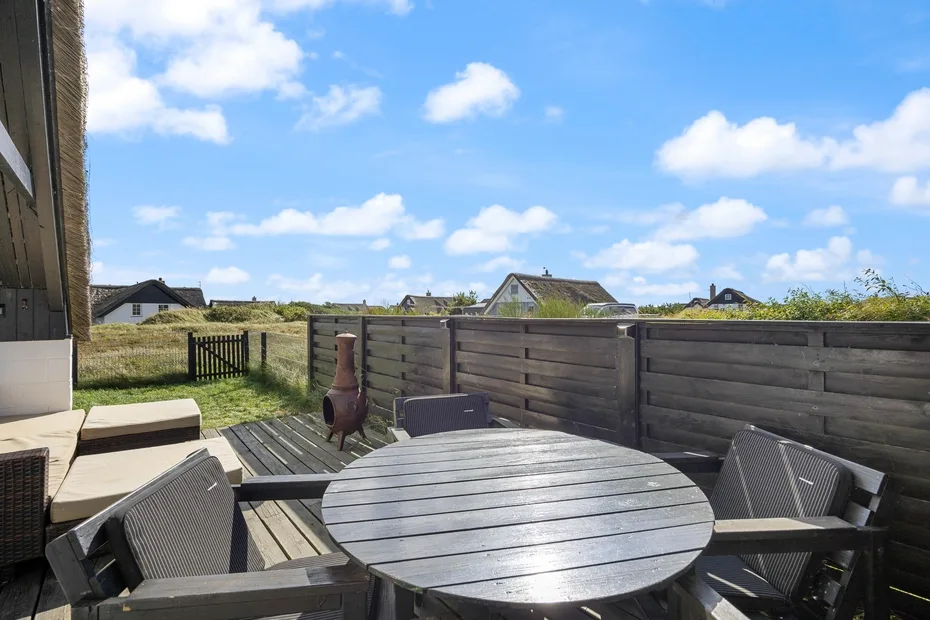 An outdoor patio with a round table and seating beside a wooden fence.