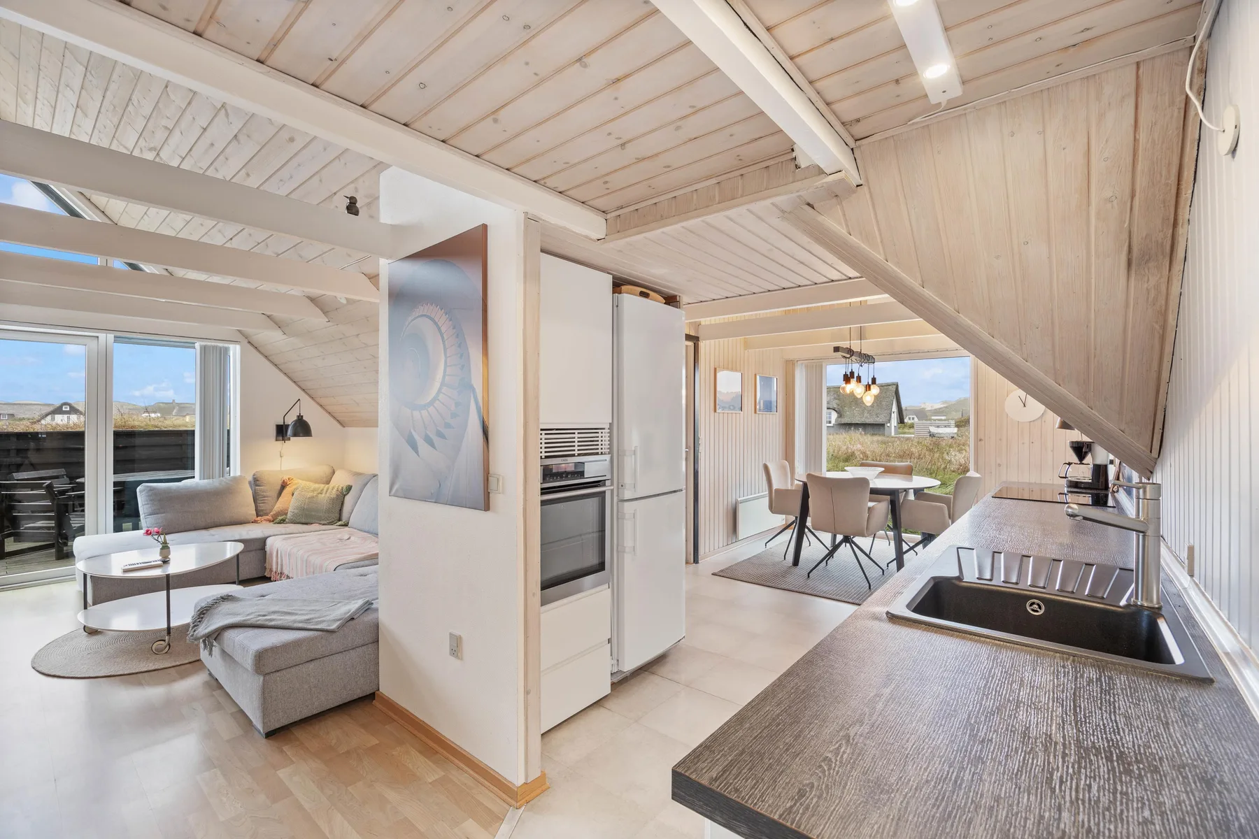 An open-plan kitchen and living area with a dining table by the windows.