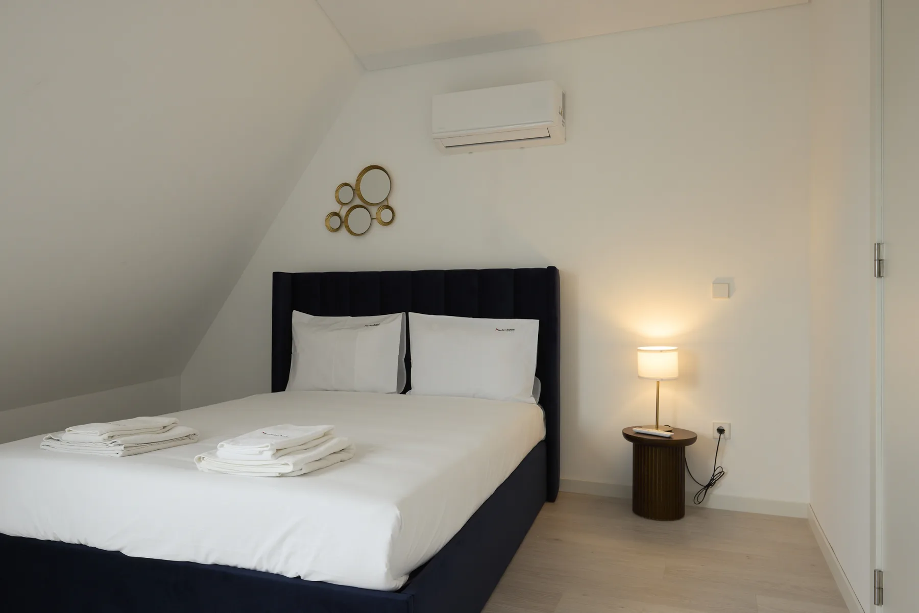A bedroom with a neatly made bed and a bedside lamp.