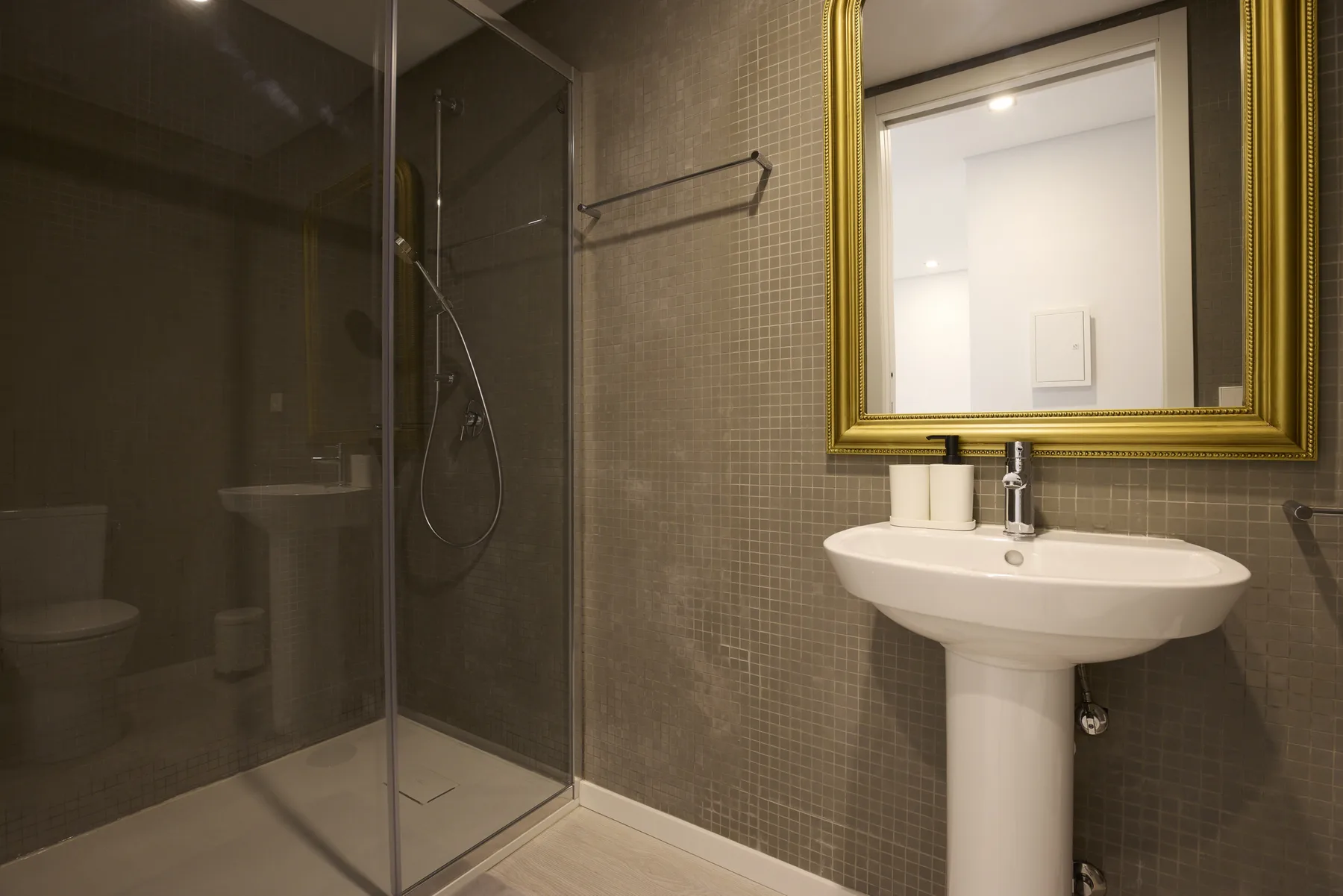 A bathroom with a glass shower and pedestal sink.
