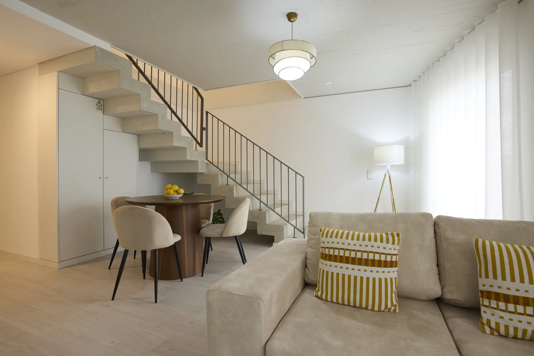 A living and dining area with seating beside a staircase.