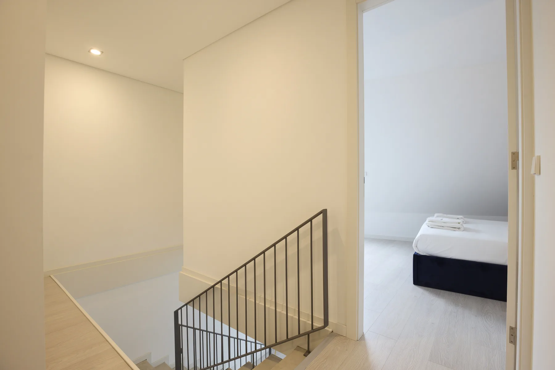 A bright upstairs hallway overlooks a staircase beside an open bedroom.