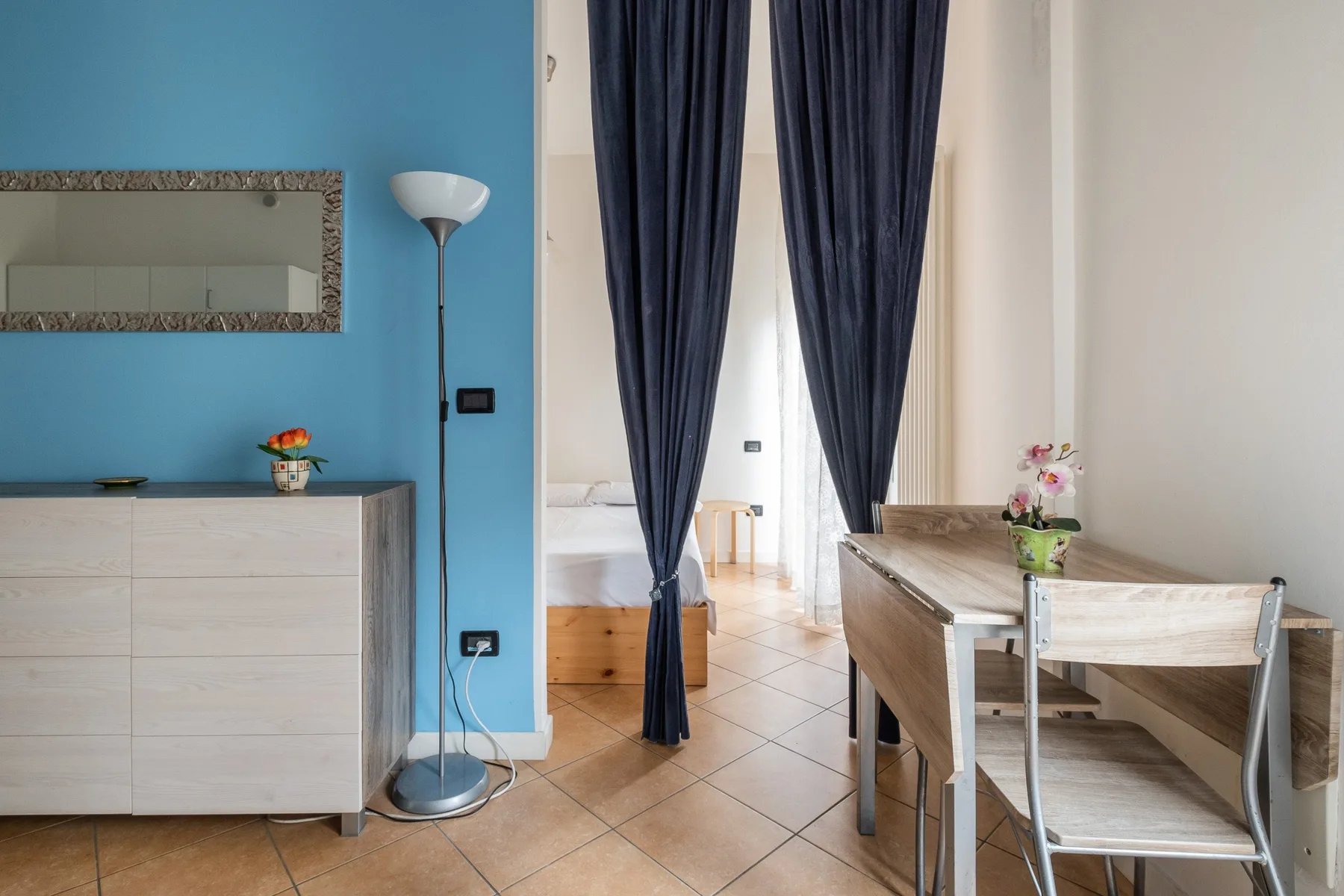 Un comedor con una mesa de madera y sillas junto a cortinas oscuras.