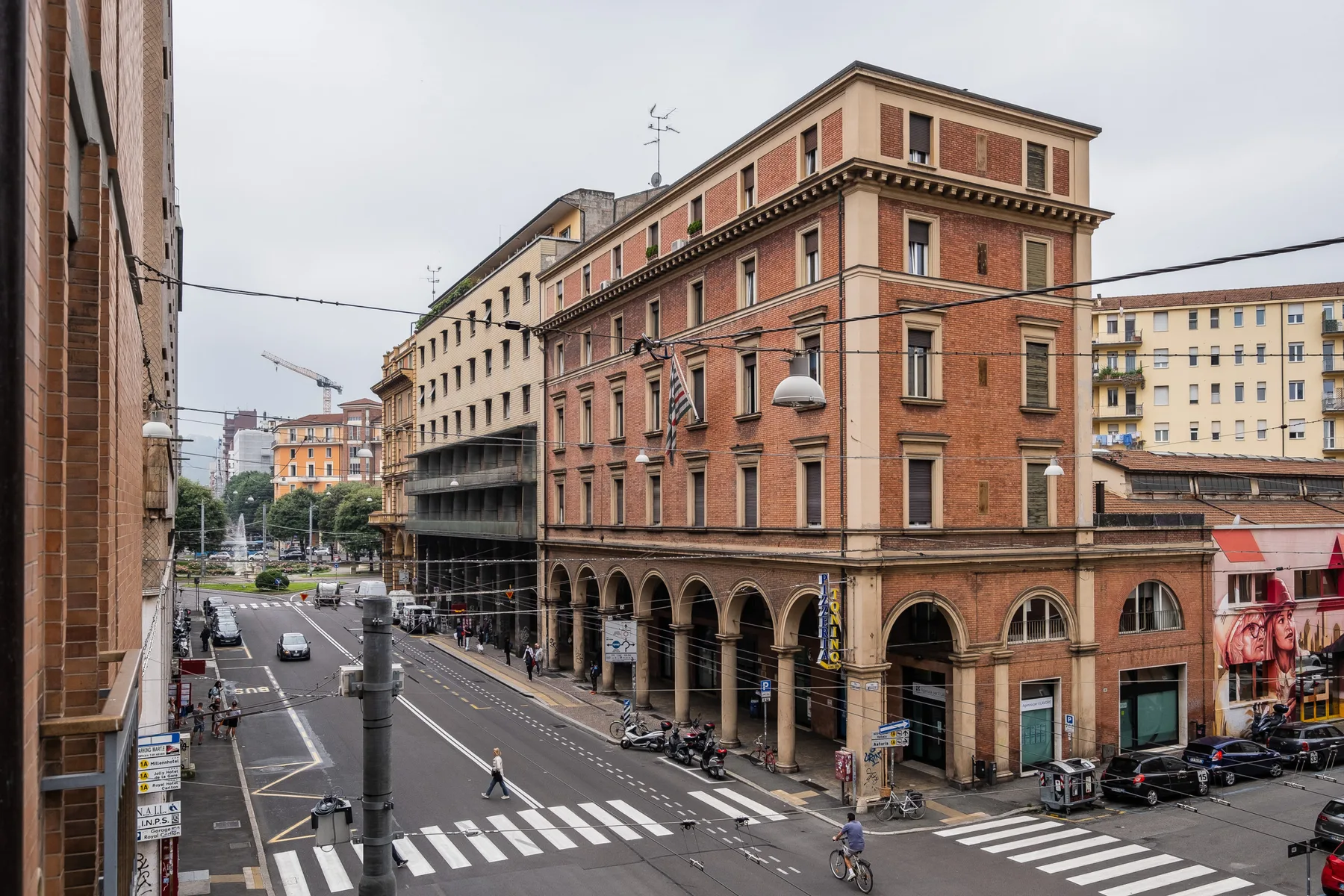 Una intersección urbana bordeada de edificios de ladrillo, con coches y peatones.