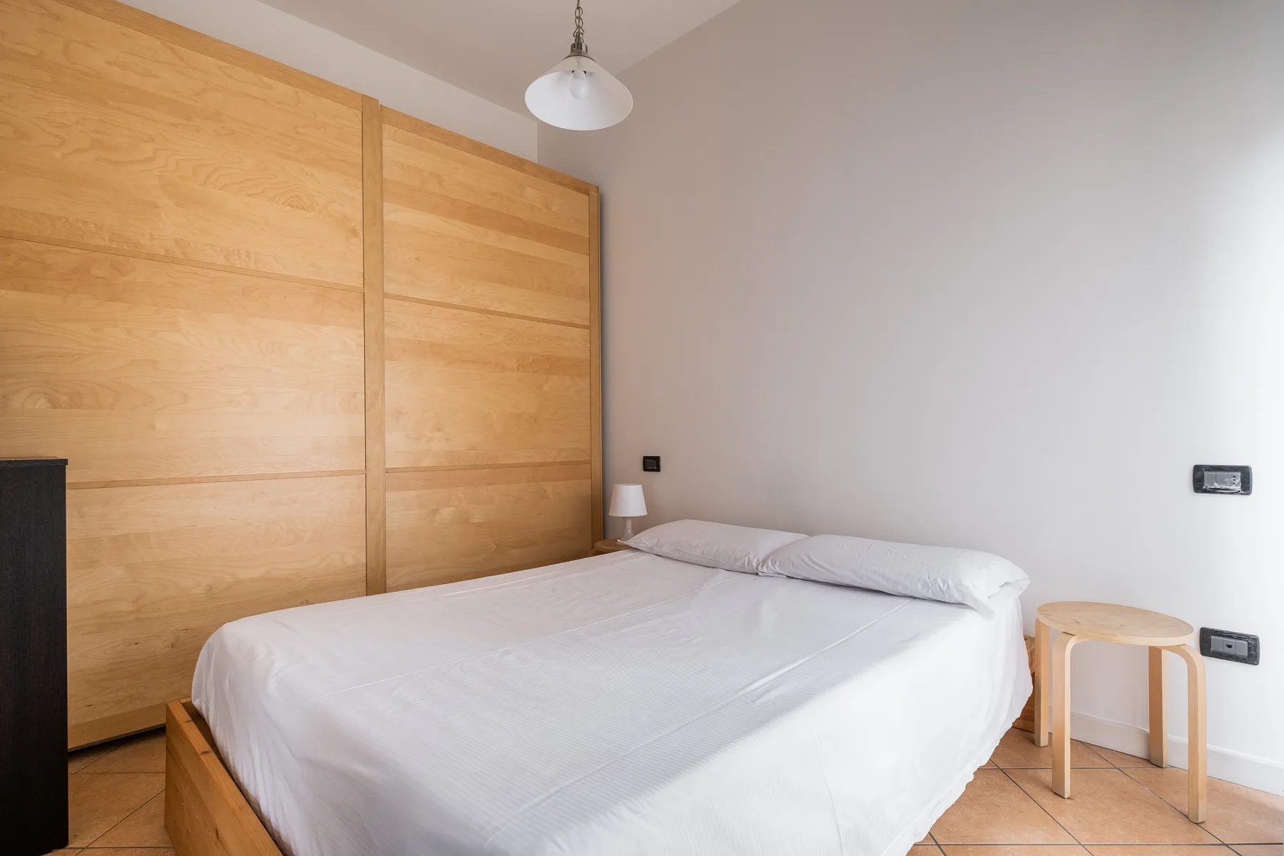 Un dormitorio con una cama, paneles de madera en la pared y una mesita redonda.