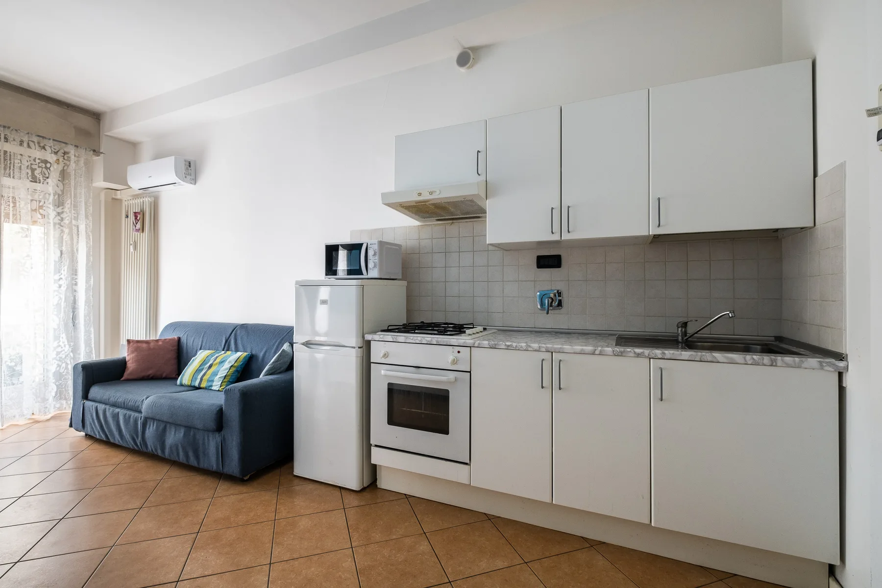 Una cocina compacta con un sofá azul junto a la zona de cocina.