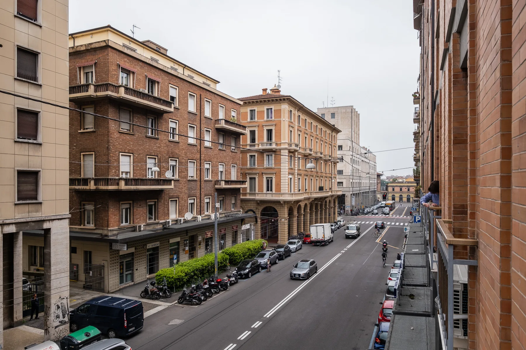 Una calle urbana bordeada de edificios de varias plantas y vehículos estacionados.