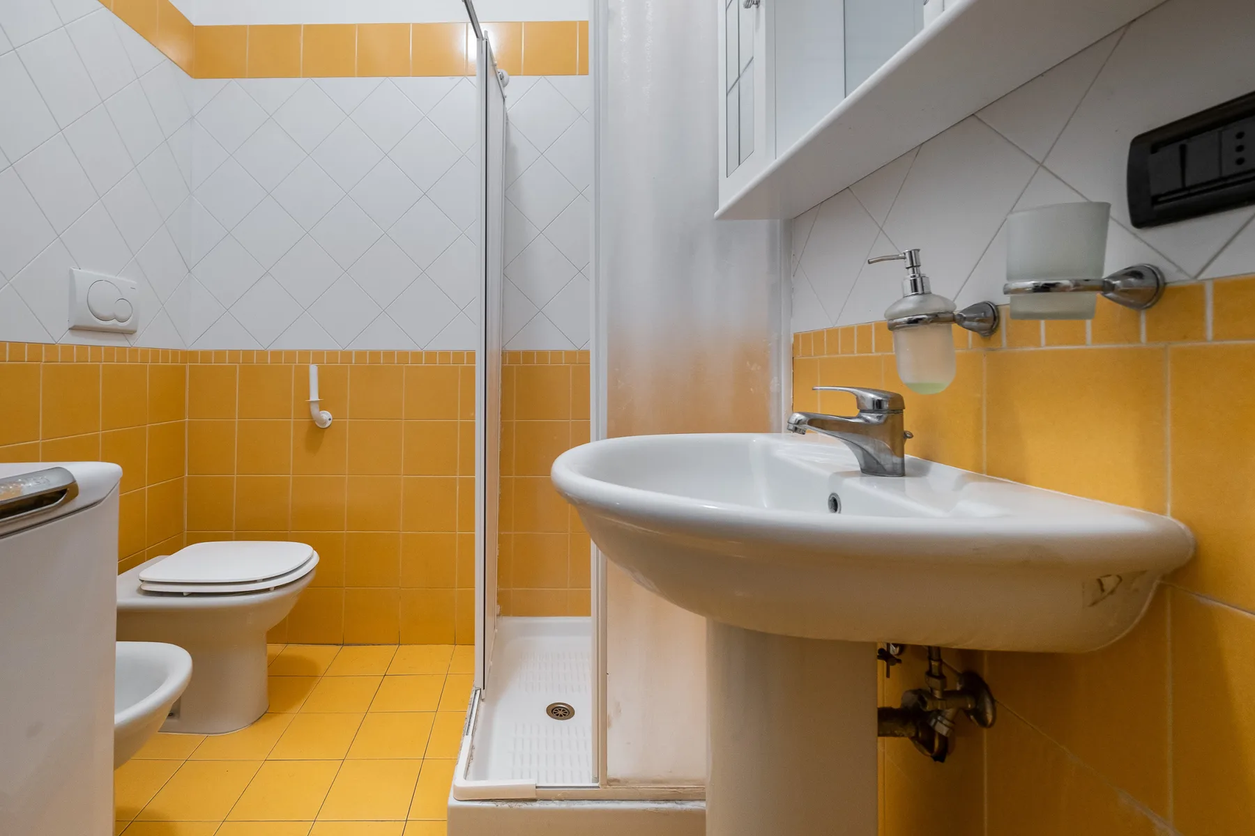 Un baño con lavabo, inodoro y ducha con mampara de vidrio.