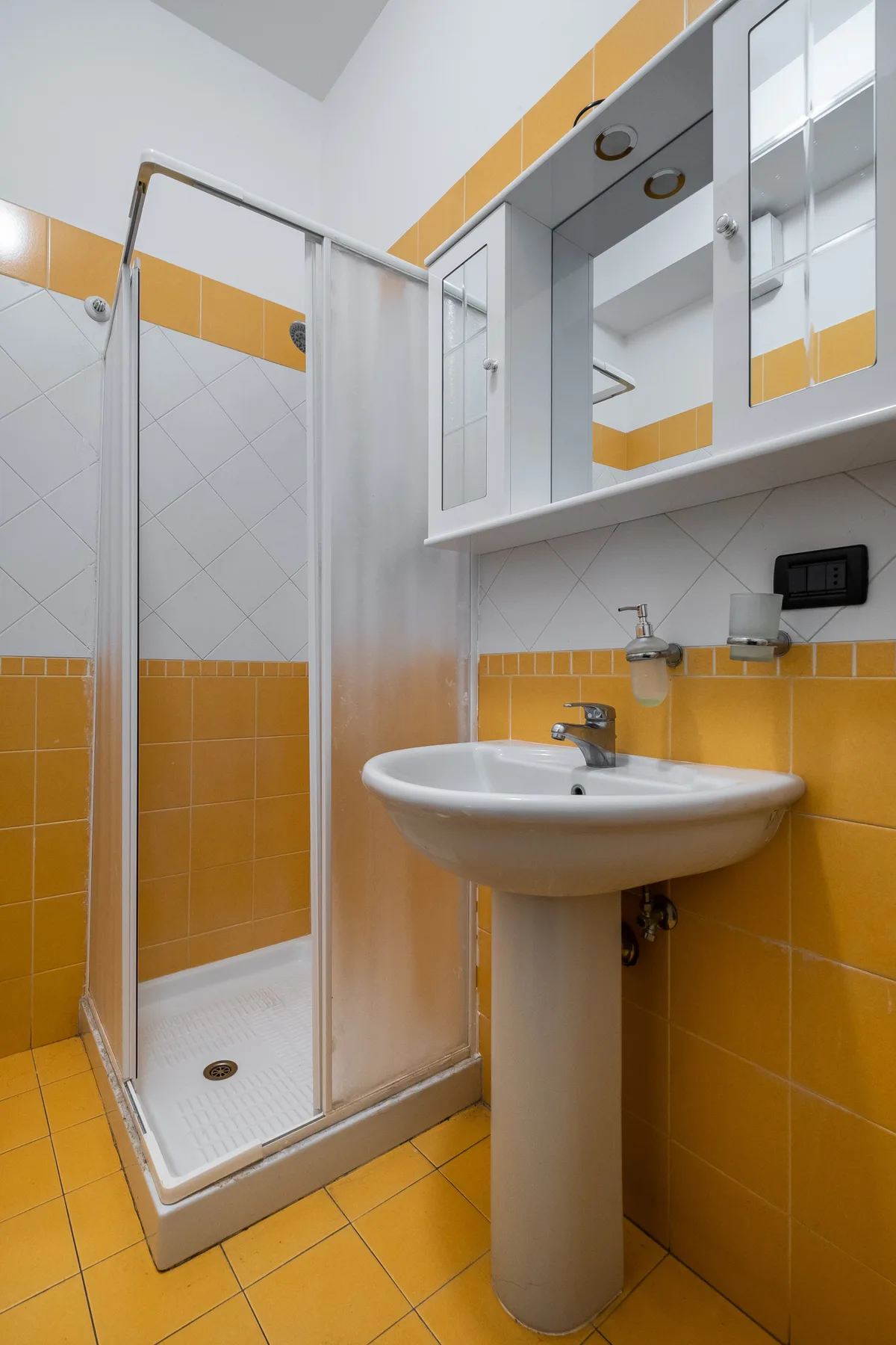 Un baño con ducha y lavabo de pedestal.
