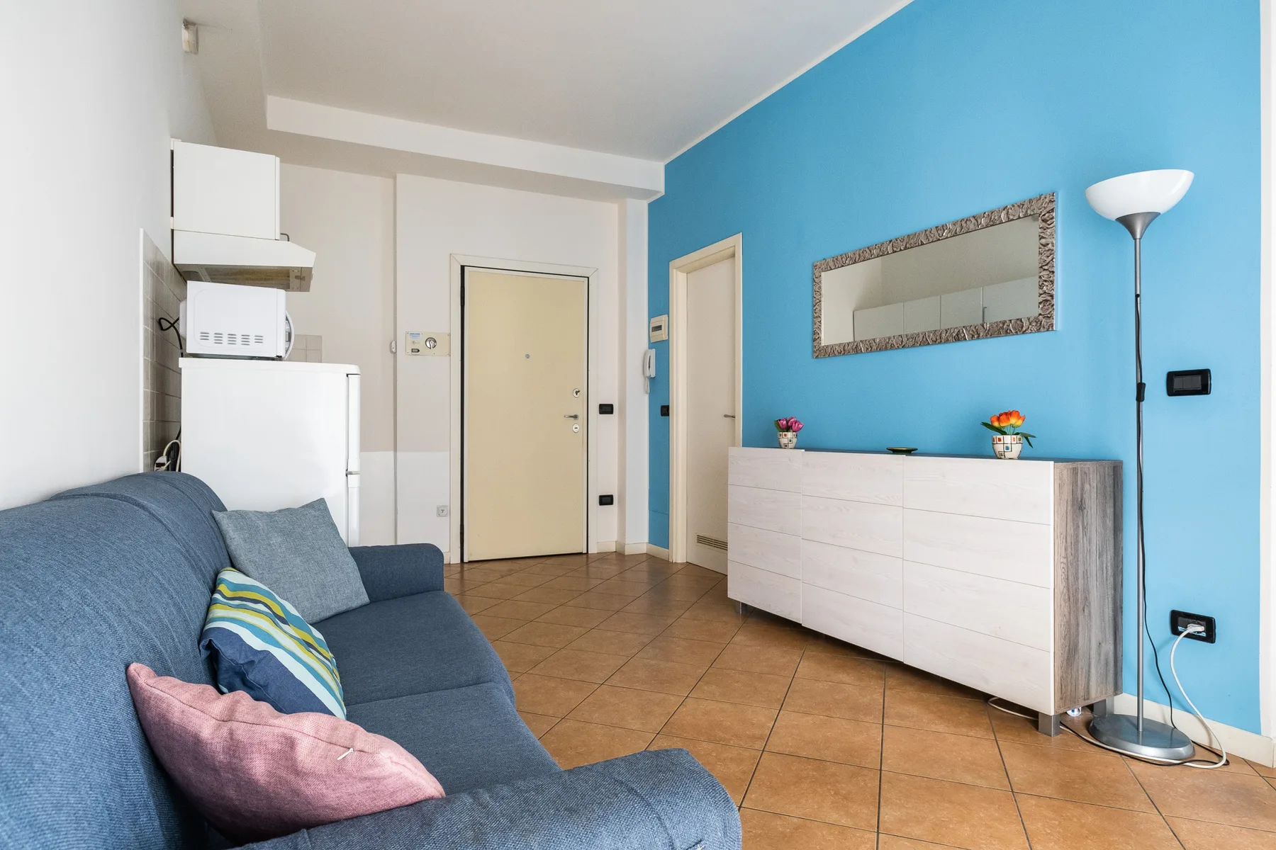 Una sala de estar con asientos azules, una cómoda y una pared azul brillante.