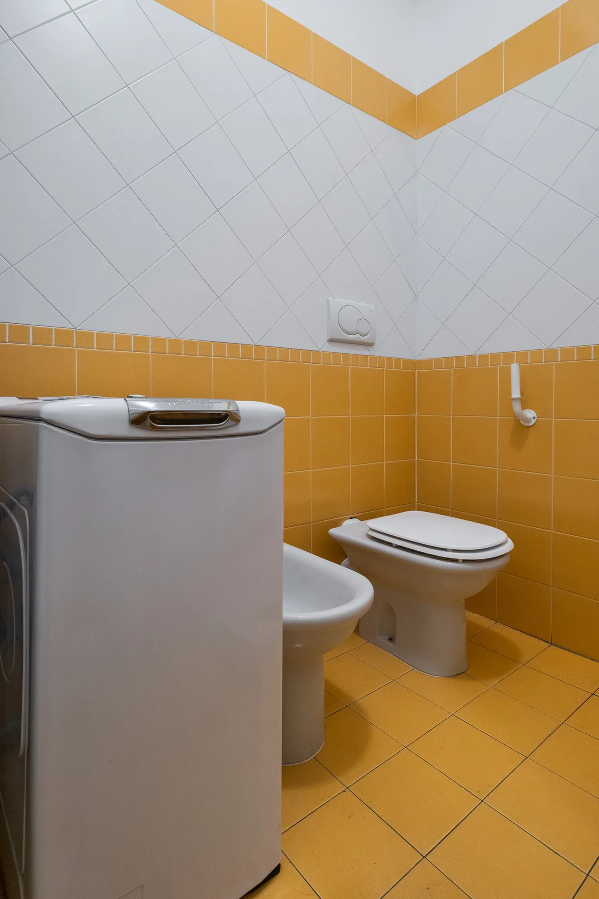 Un baño alicatado con un inodoro y un bidé parcialmente visible.