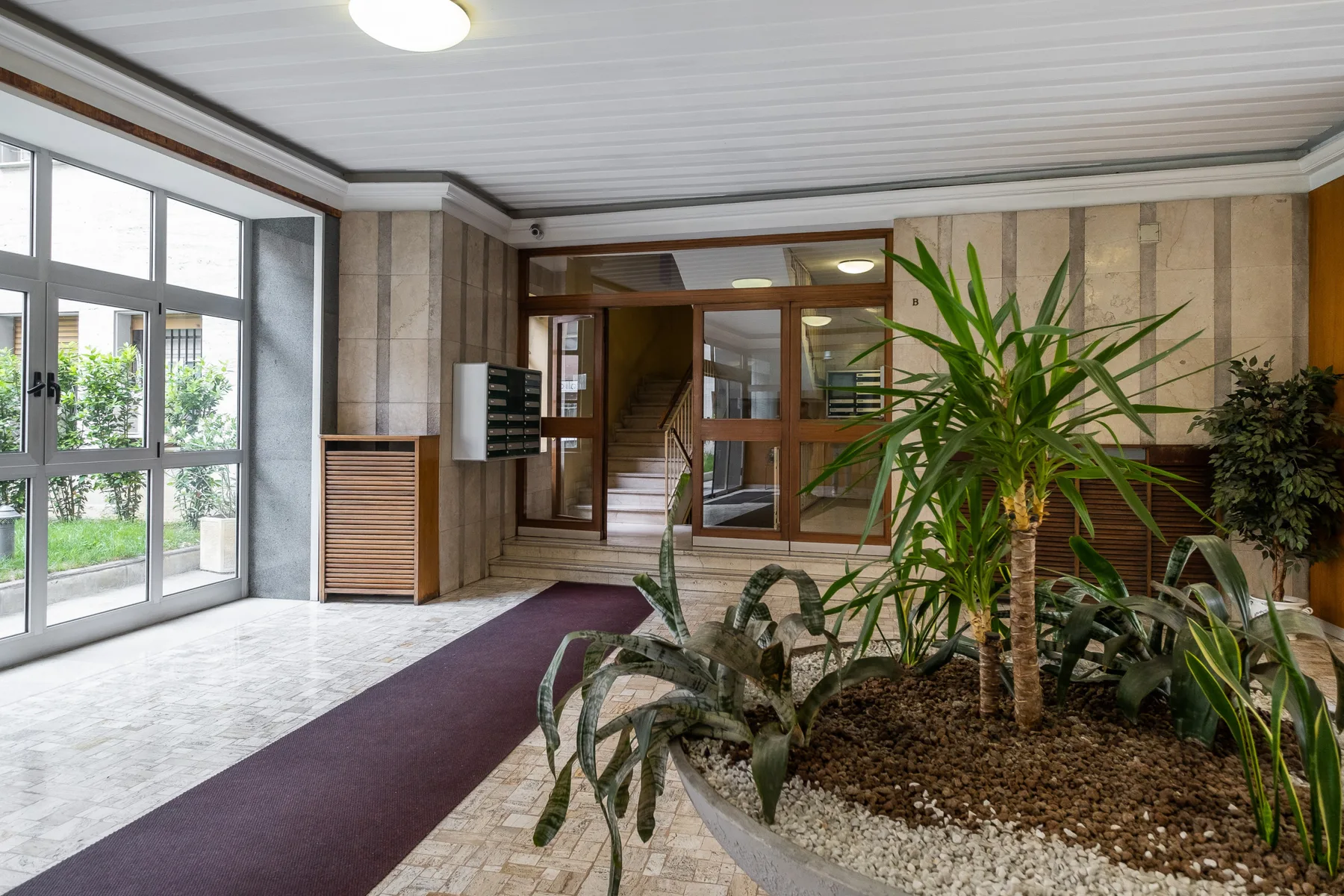 Un vestíbulo con un jardín interior junto a grandes ventanas.
