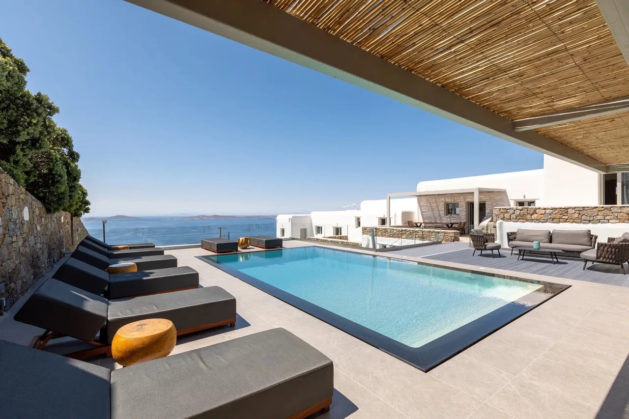 A rooftop pool terrace with lounge seating overlooks the sea.