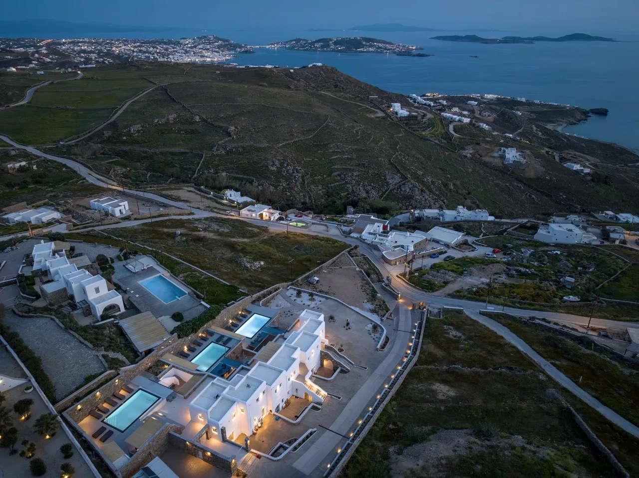 An aerial view of hillside buildings beside a coastal bay.