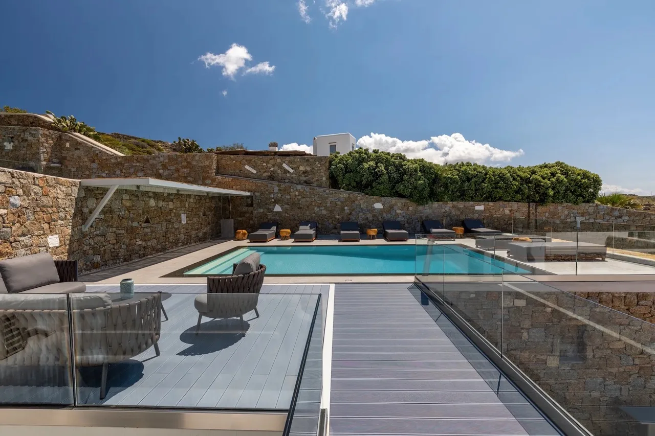 Outdoor pool area with lounge seating and a glass-sided walkway.