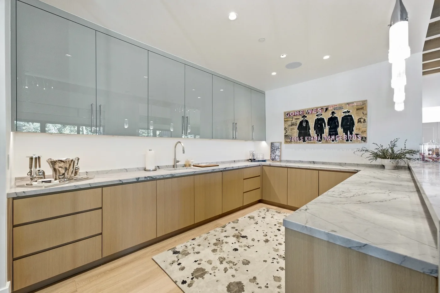 A modern kitchen with light wood cabinetry and a large stone island.