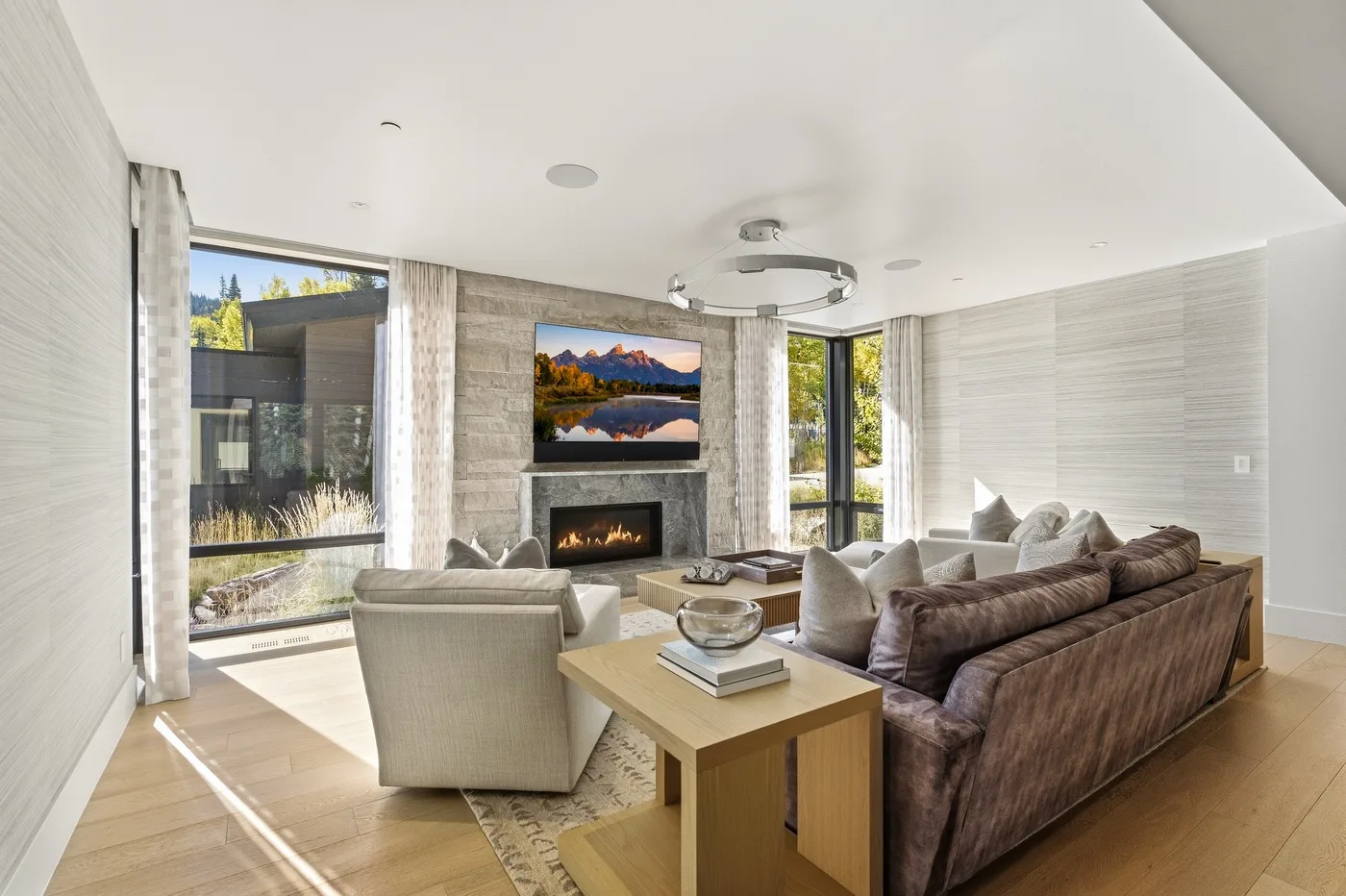 A bright living room with seating arranged around a fireplace and television.