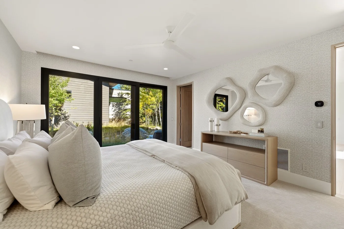 A bright bedroom with a large bed facing glass doors to a garden.