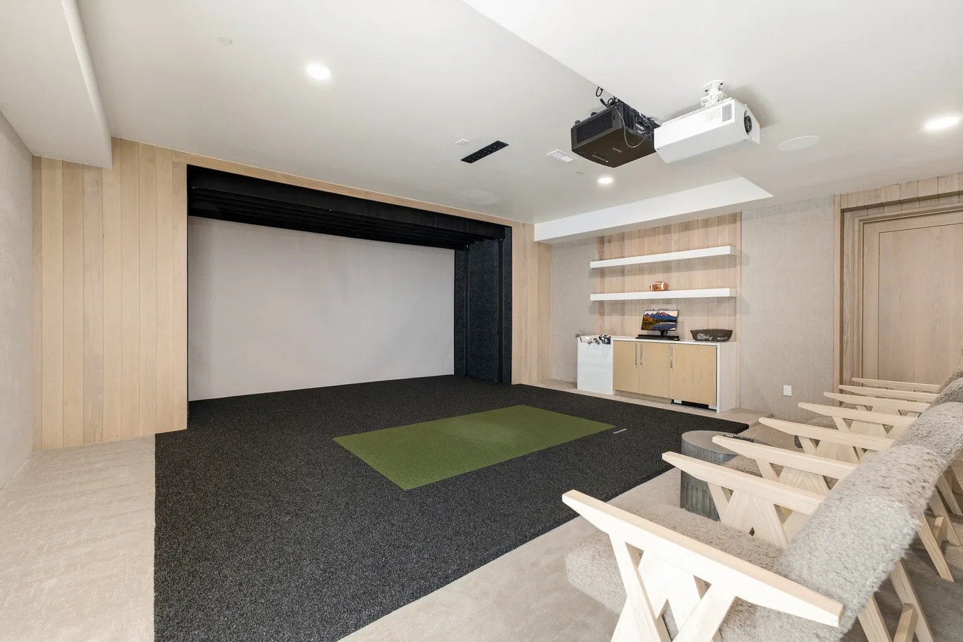 A small screening room with a projection screen and rows of seating.