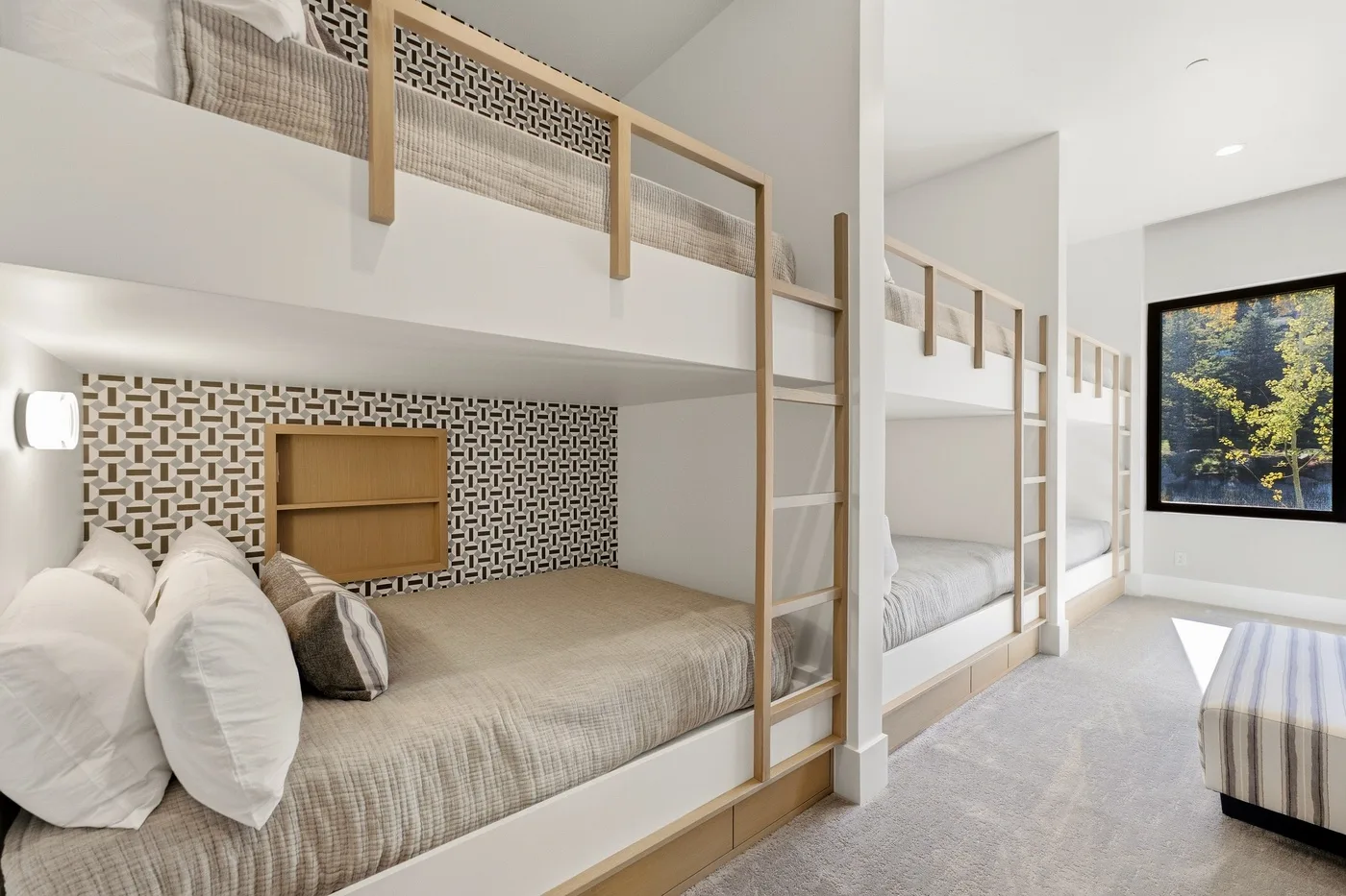 A bright bedroom with built-in bunk beds and a large window overlooking trees.