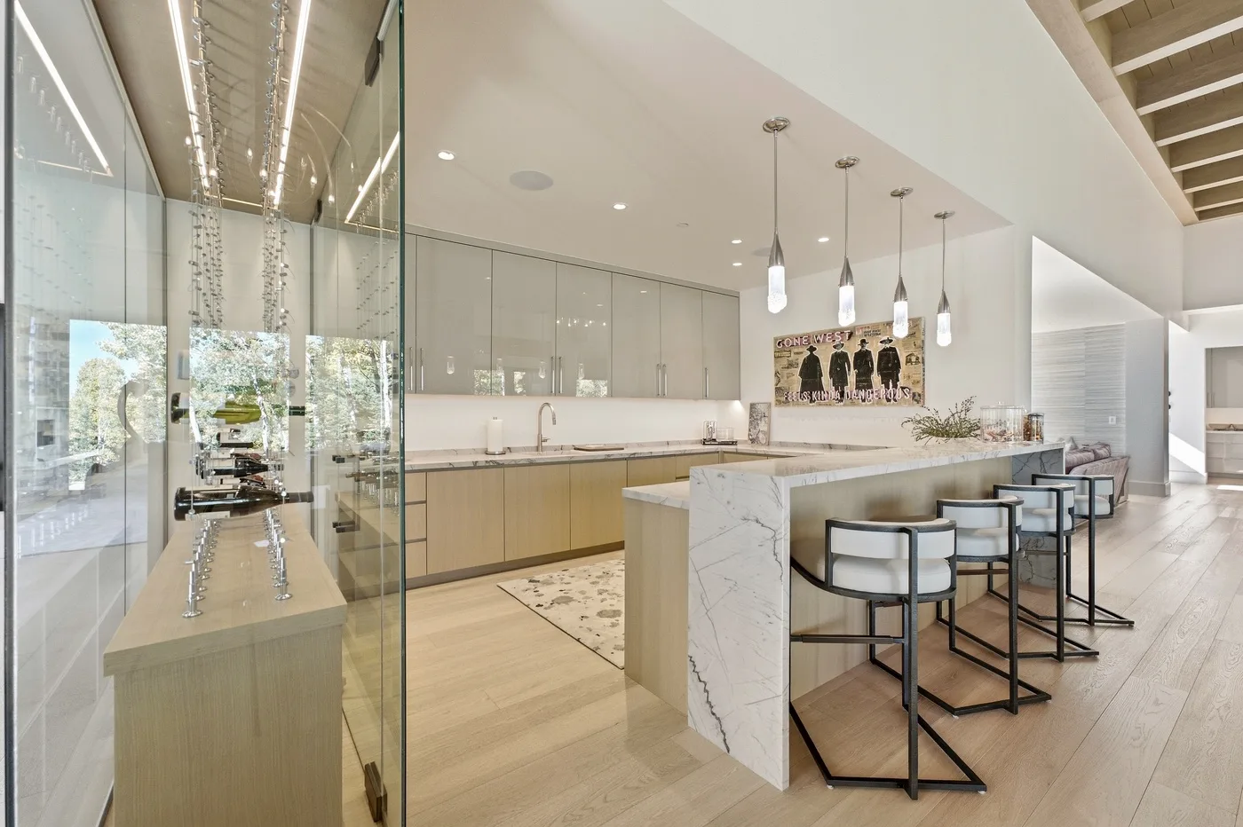A bright modern kitchen and dining area with a marble island and bar seating.
