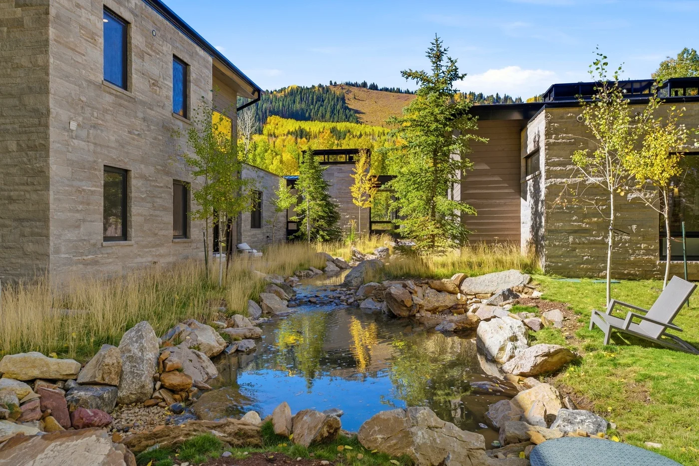 A landscaped outdoor courtyard with a narrow stream winding between modern buildings.