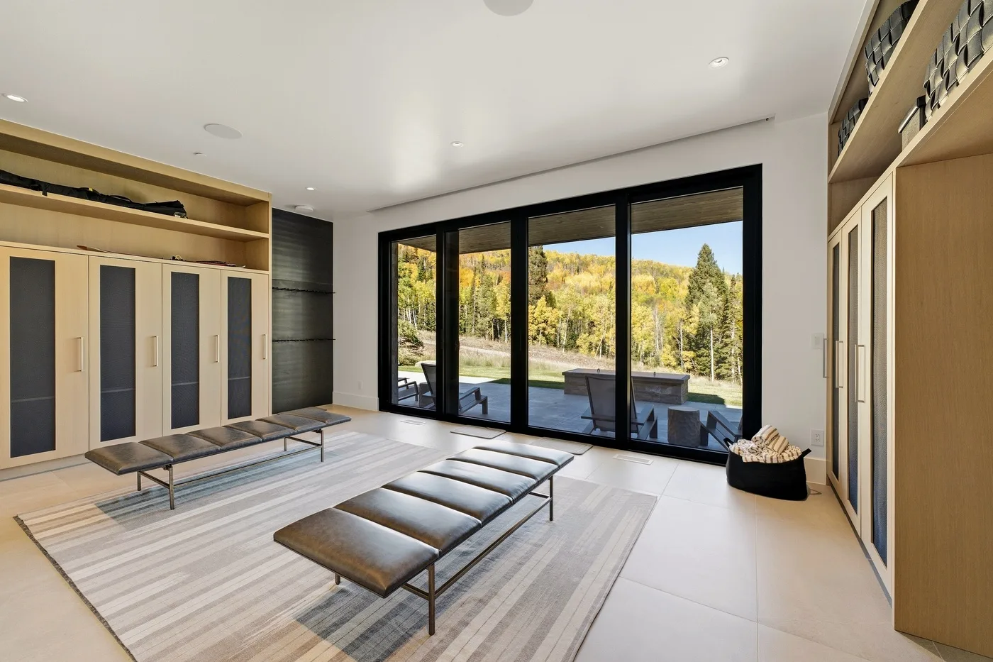 A bright dressing room with built-in wardrobes and large windows overlooking trees.