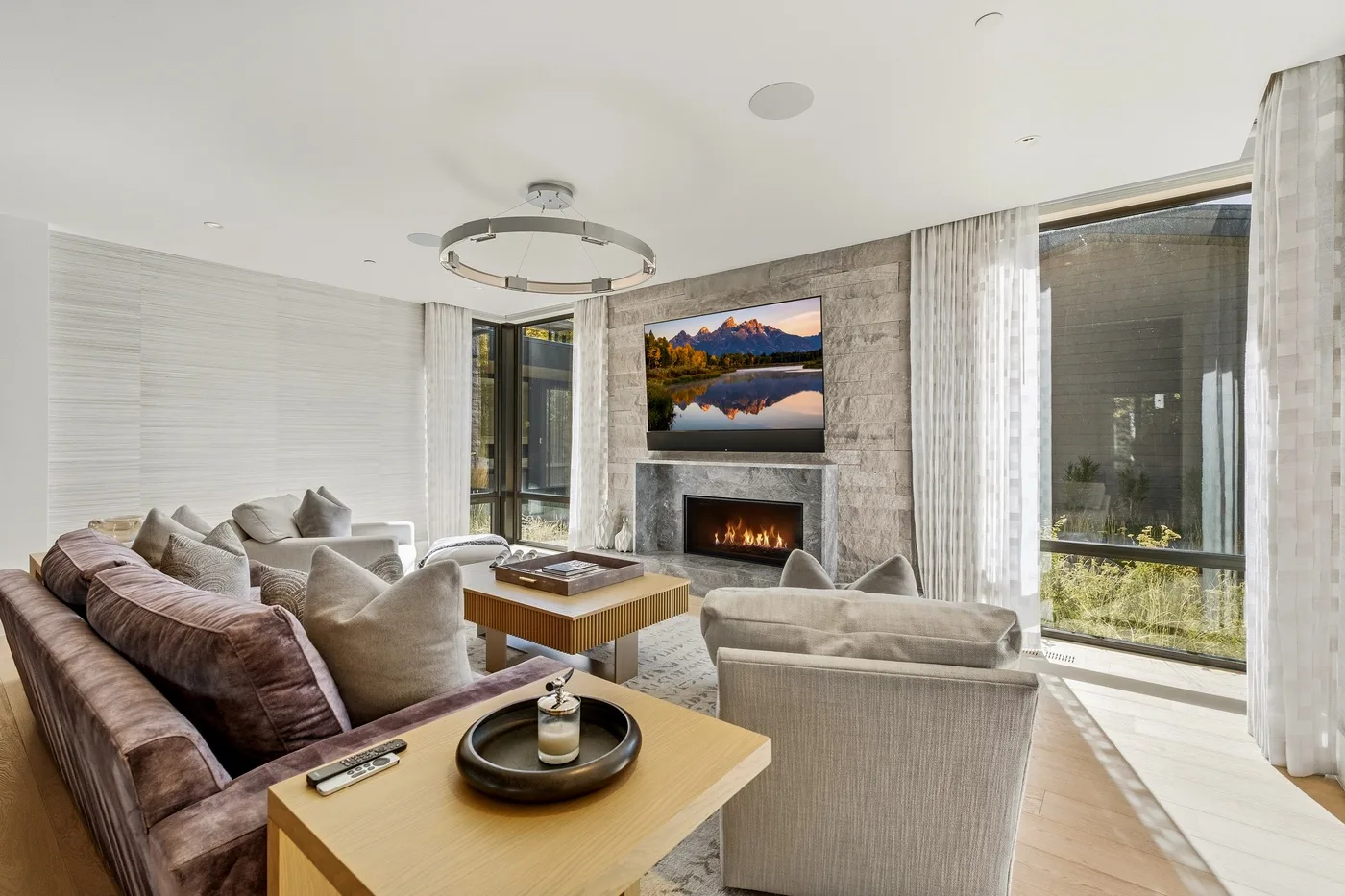 A bright living room with seating arranged around a fireplace and television.