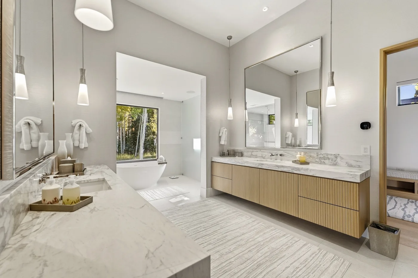 A bright bathroom with a long vanity, large mirror, and bathtub.