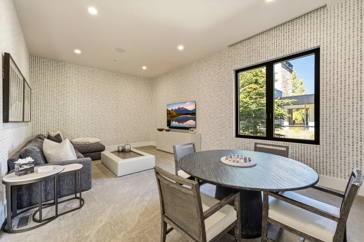 A dining area with a round table and seating beside a living area.