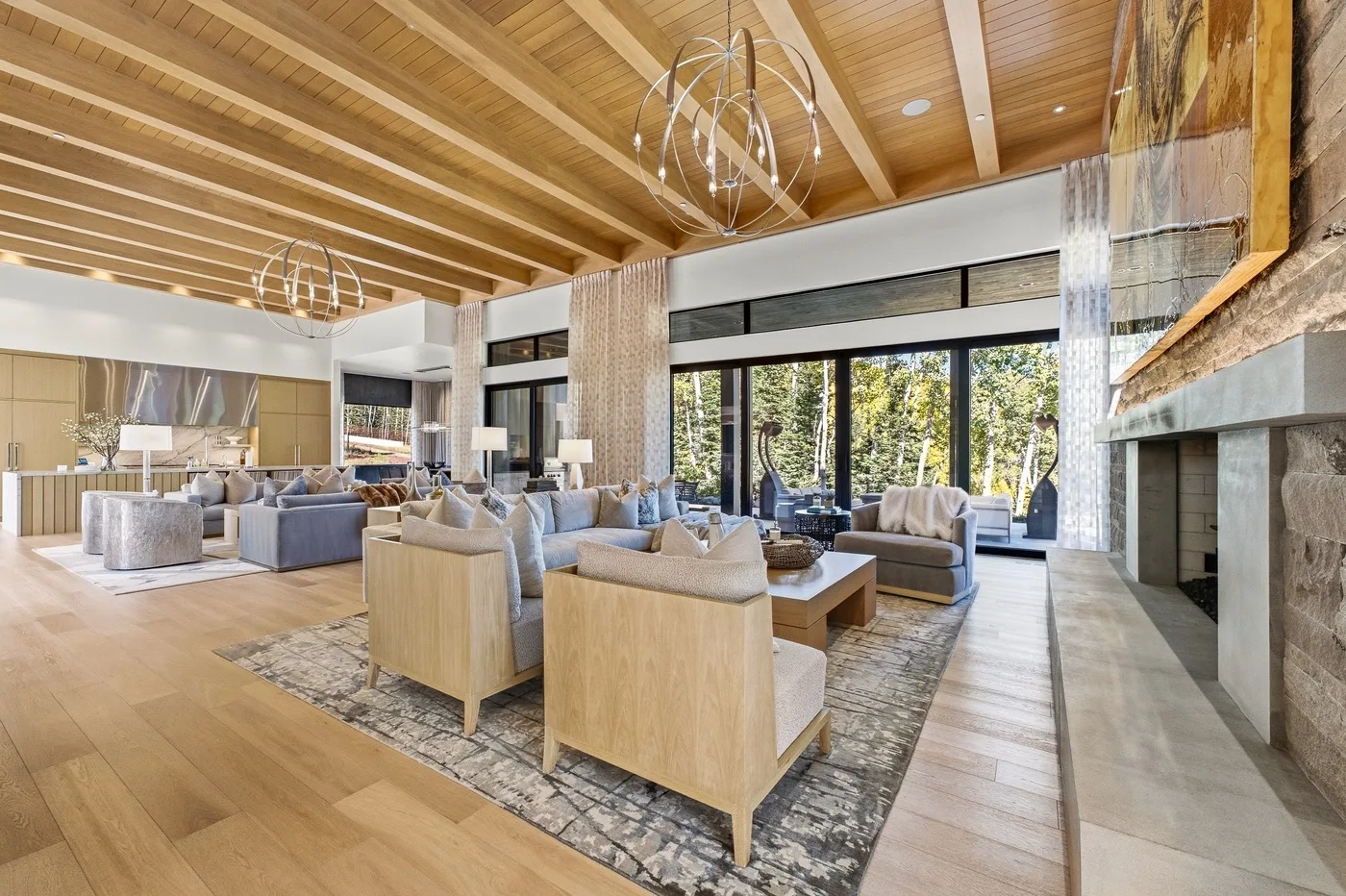 A spacious living room with seating arranged around a coffee table and a large fireplace.