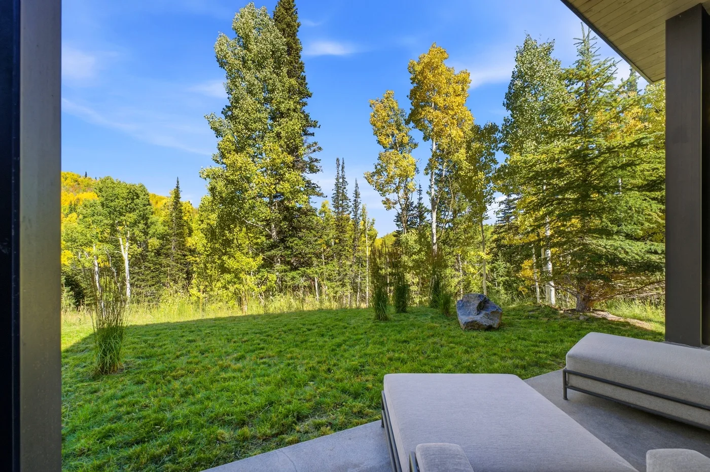A patio seating area overlooks a grassy yard with trees.