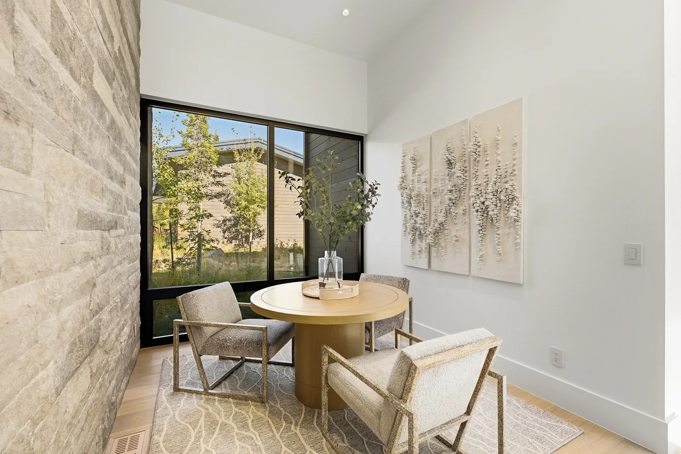 A bright dining area with a round table beside large windows.