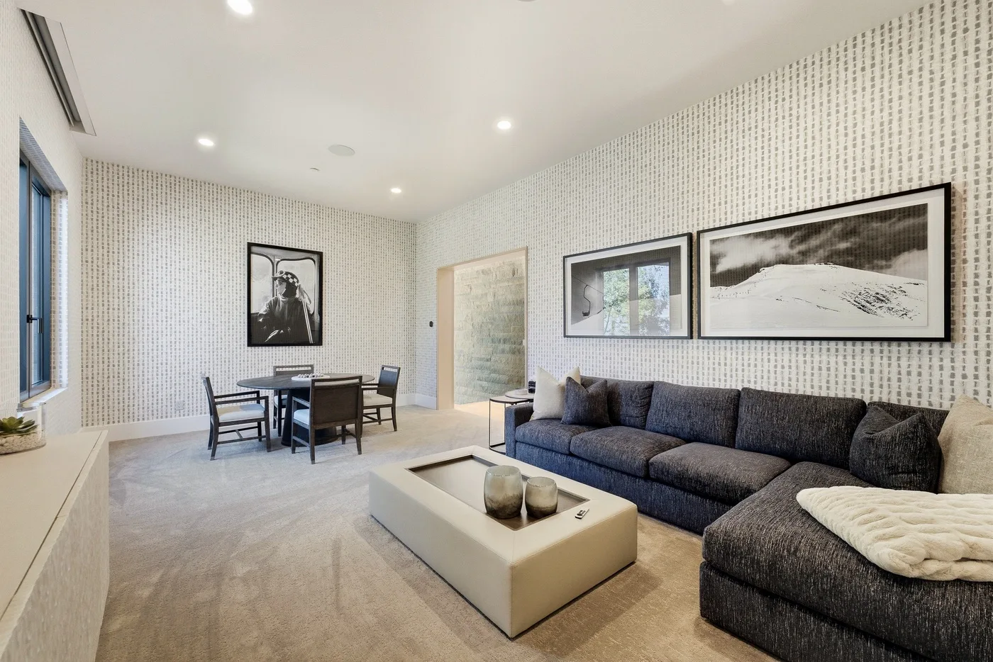 A bright living room with a sectional sofa, coffee table, and dining area.