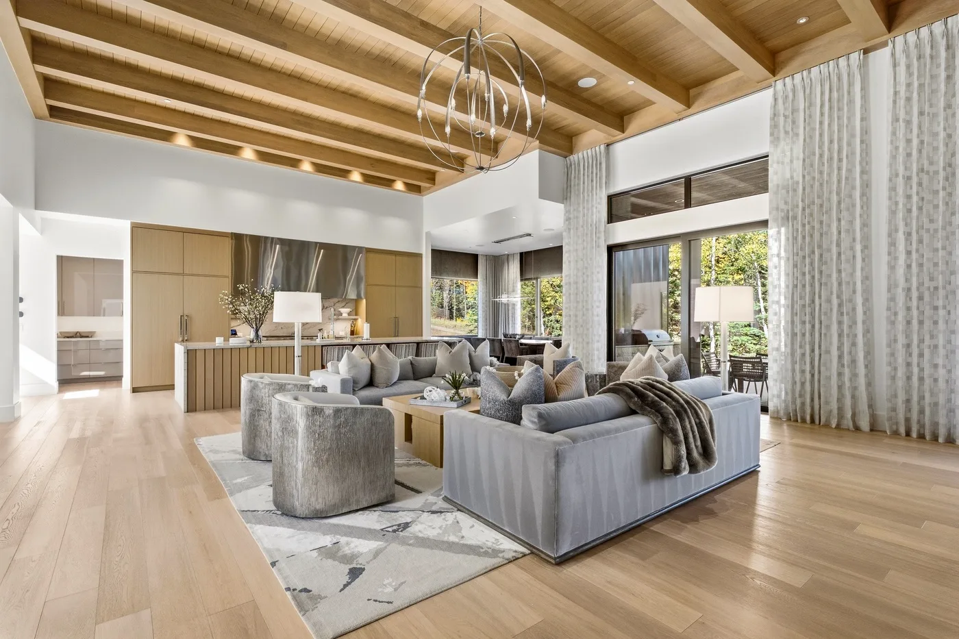 A bright living room with seating beneath a high wood-beamed ceiling.