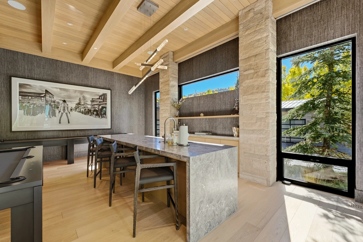 A modern kitchen and dining area with a long counter and large windows.