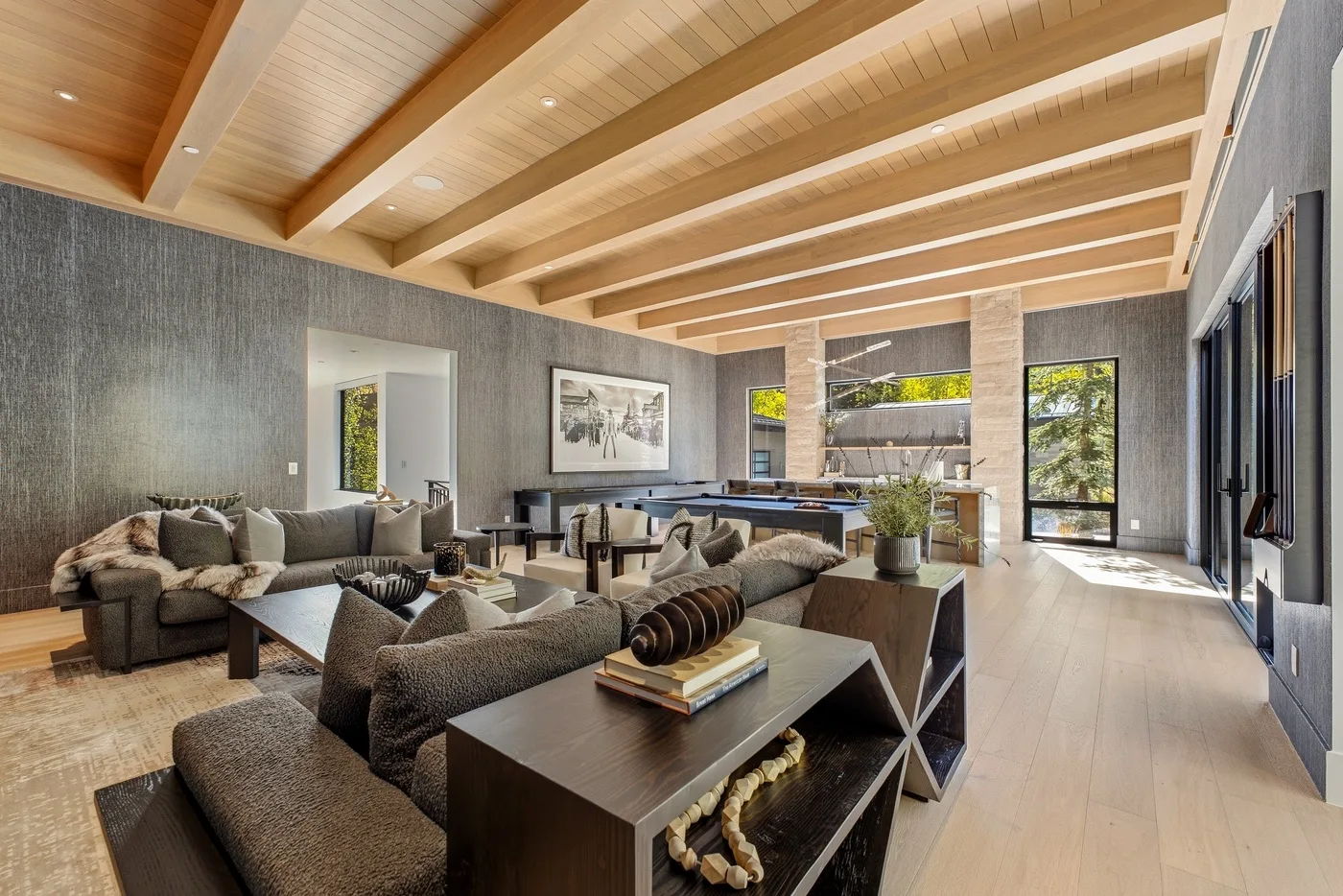 A spacious living room with seating, a coffee table, and exposed ceiling beams.